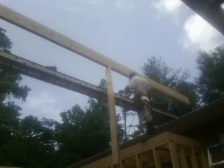 Carpenter setting a ridge beam over a new addition frame — Ice Dam Removal by Roofing Brothers in Oak View