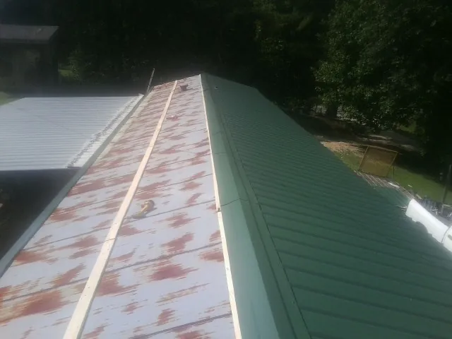 Old rusted panels beside newly installed green metal roofing — Wind Damage Roof Repair by Roofing Brothers in Oak View