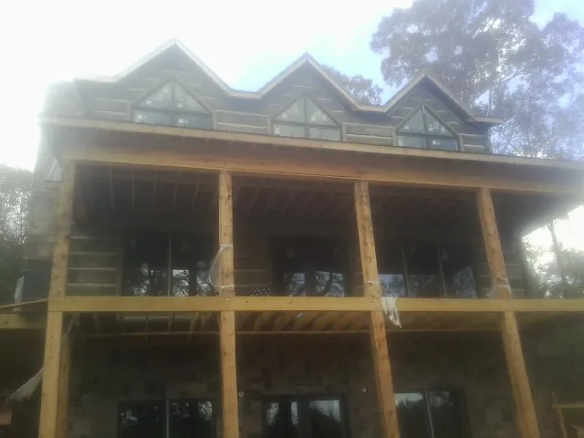 Dormers and porch framing on a large log home under construction — Roof Coating work by our crew in Oak View