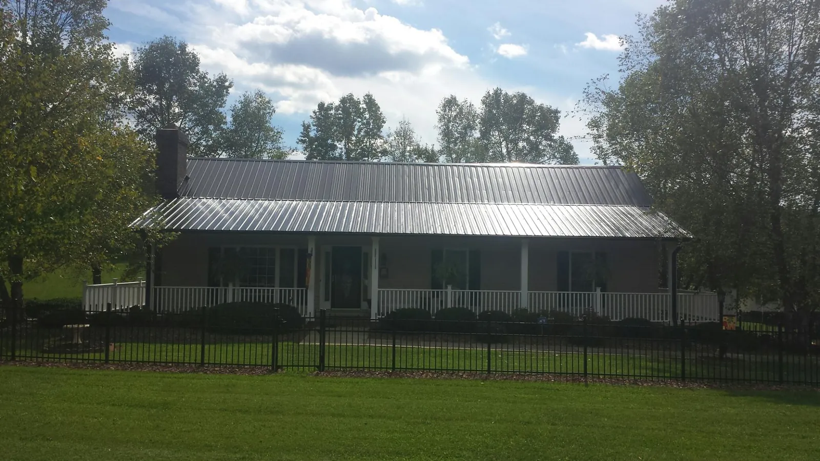 Gray metal roof on a brick ranch with a full width front porch — Gutter Guard Installation work by our crew in Oak View